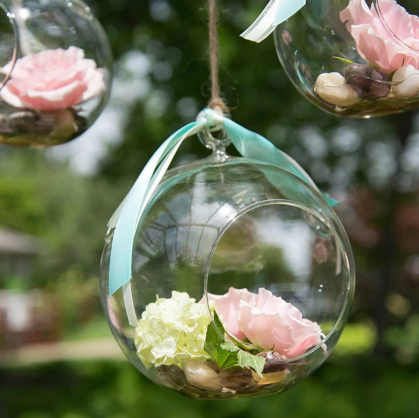 pink and white flowers resting in a small, round hanging terrarium