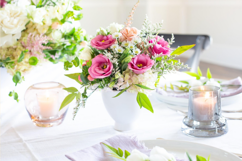 Pink flowers in a white vase on a set table