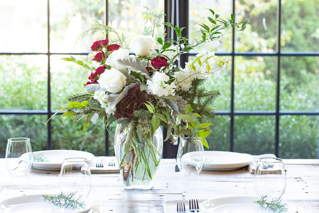 Red and white flowers in a glass vase on a set table