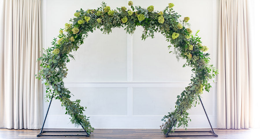 A affordable hexagonal wedding arch covered in greenery