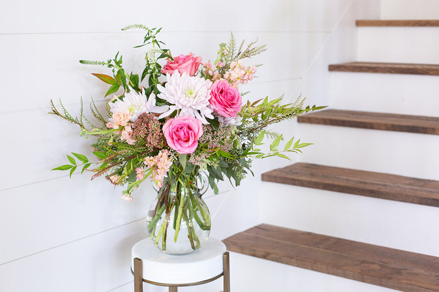 Bouquet of pink and white flowers and green leaves in a clear bubble style vase