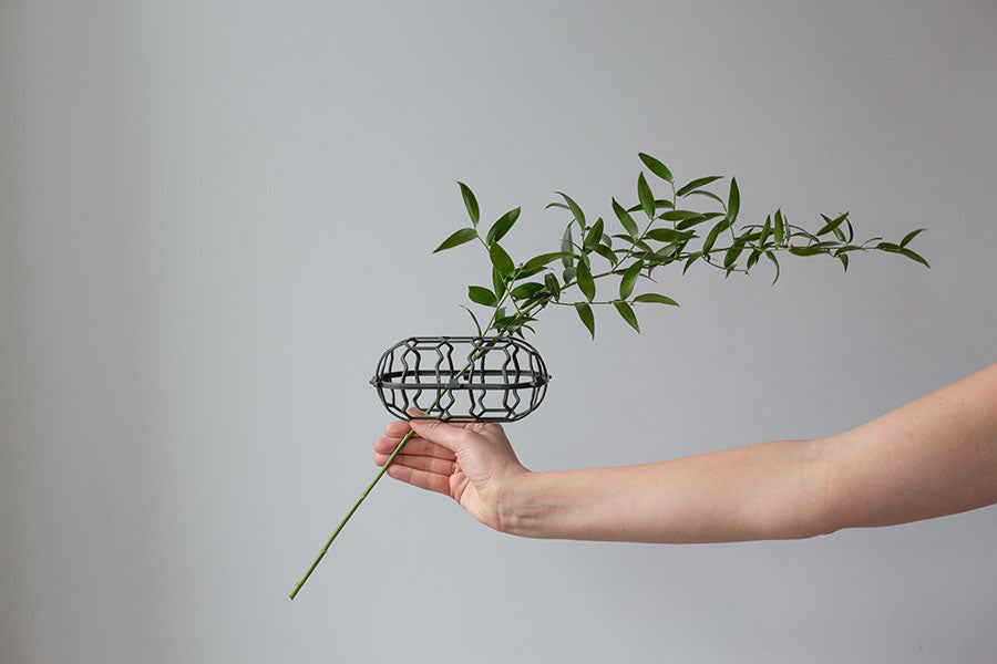 Hand holding first piece of greenery placed into the Holly Chapple Egg mechanic