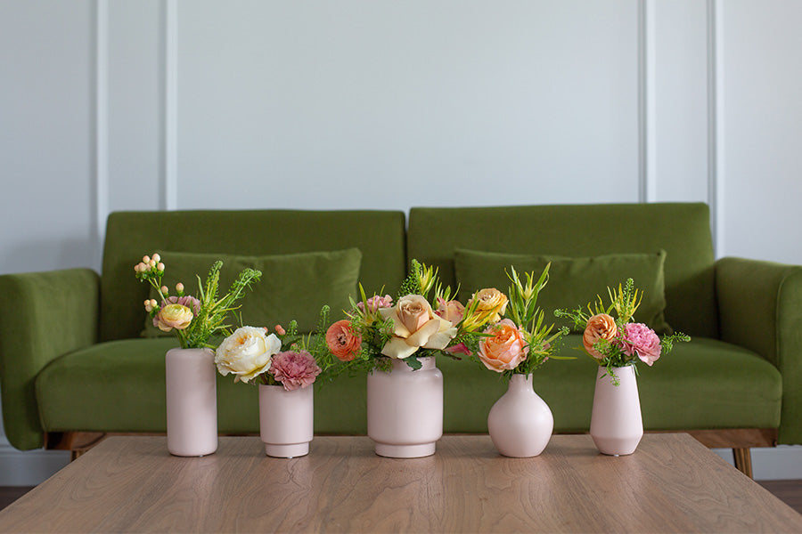 Collection of ceramic vases on a table in front of green sofa