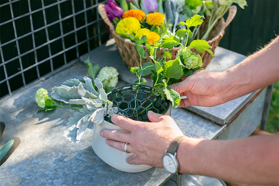 A florist working on a floral centerpiece using a Holly Chapple Pillow