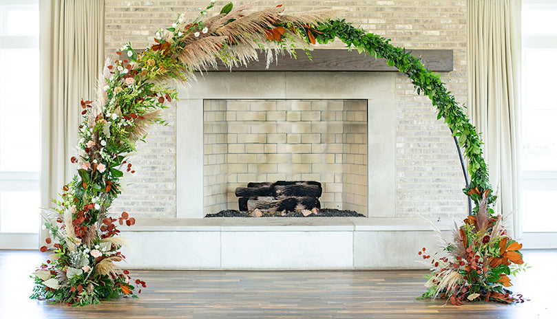 A large floral wedding arch in front of a fireplace for a wedding.