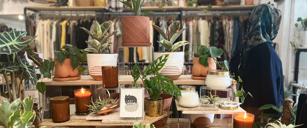 A view from the Shudio Shop floor, containing candles by local makers, vintage clothing, planters and plants