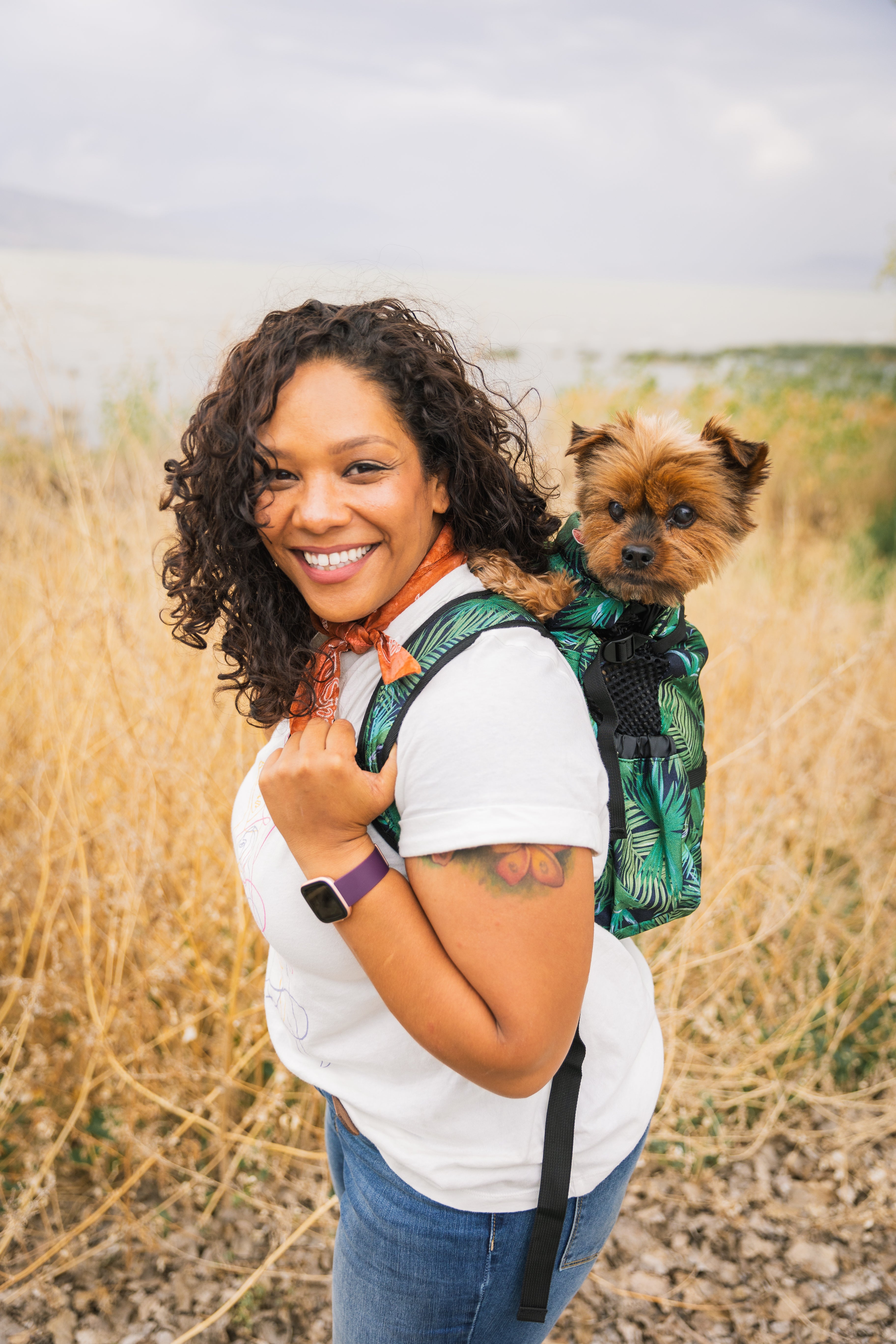 A woman stands outside with a tropical Air 2 backpack dog carrier