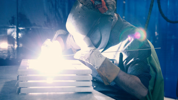 employee welding dog crate doors in impact dog crates idaho facility