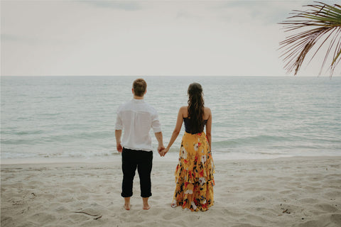 pareja agarrada de mano en la playa mirando al mar