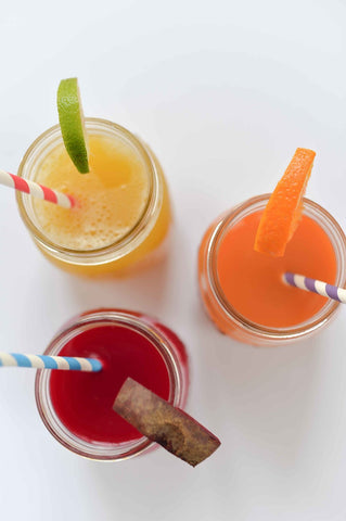 tres jugos con rodajas: jugo de limón y piña, jugo de naranja y zanahoria, jugo de remolacha y zarzamora.