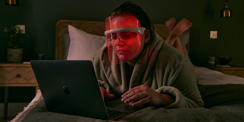 Woman wearing Get Lit LED Face Mask while on laptop
