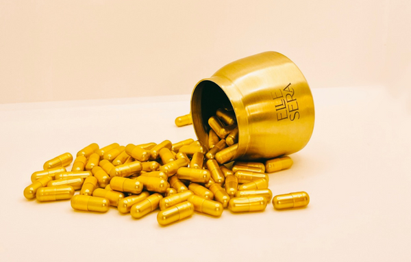 A brass pot of Elle Sera pills tipped over with pills poured out of it