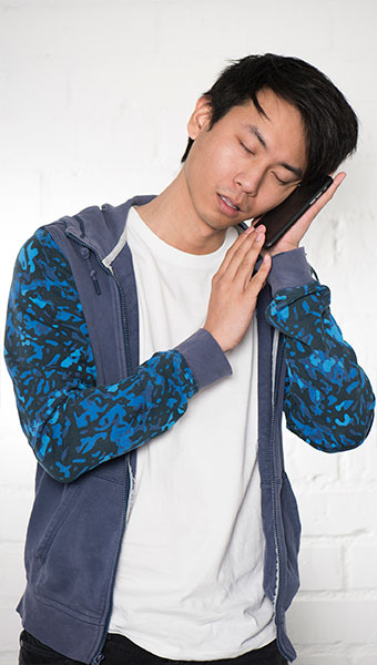 Portrait of a man sleeping on an iPhone case in front of exposed brick wall