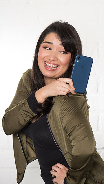 Portrait of a woman with an iPhone case on her shoulder in front of exposed brick wall