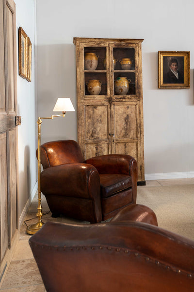 French leather club chair in living room with rustic antique bookcase