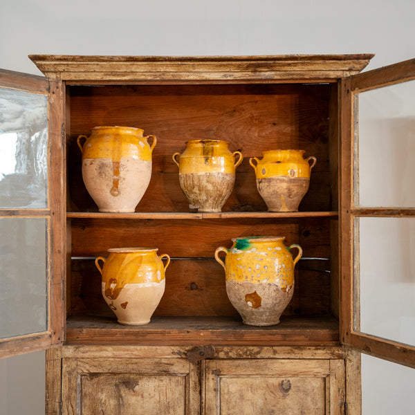 Collection of antique French confit pots in antique bookcase