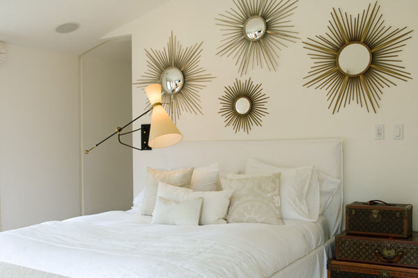Gallery wall of sunburst mirrors in modern white bedroom