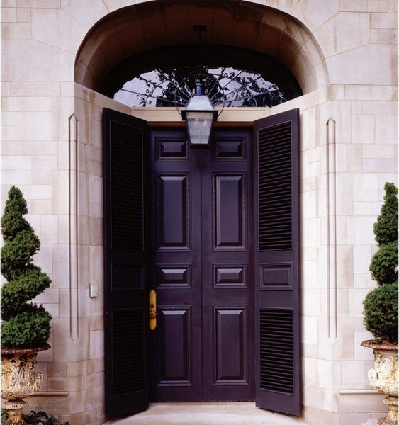 Black front door in Paris with topiary and Medici urns 