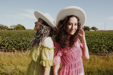 two girls with hats on in a field