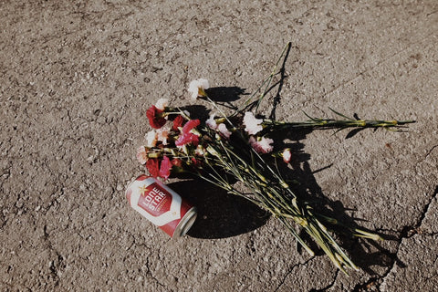 beer can and flowers on the ground