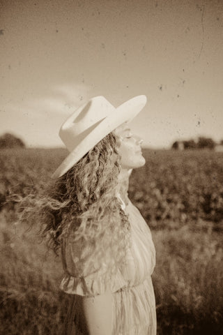 girl standing in field with hat on