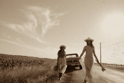 two girls walking towards camera with a truck in the background