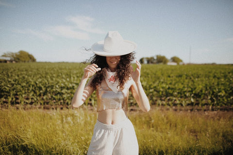 girl standing in field with hat on