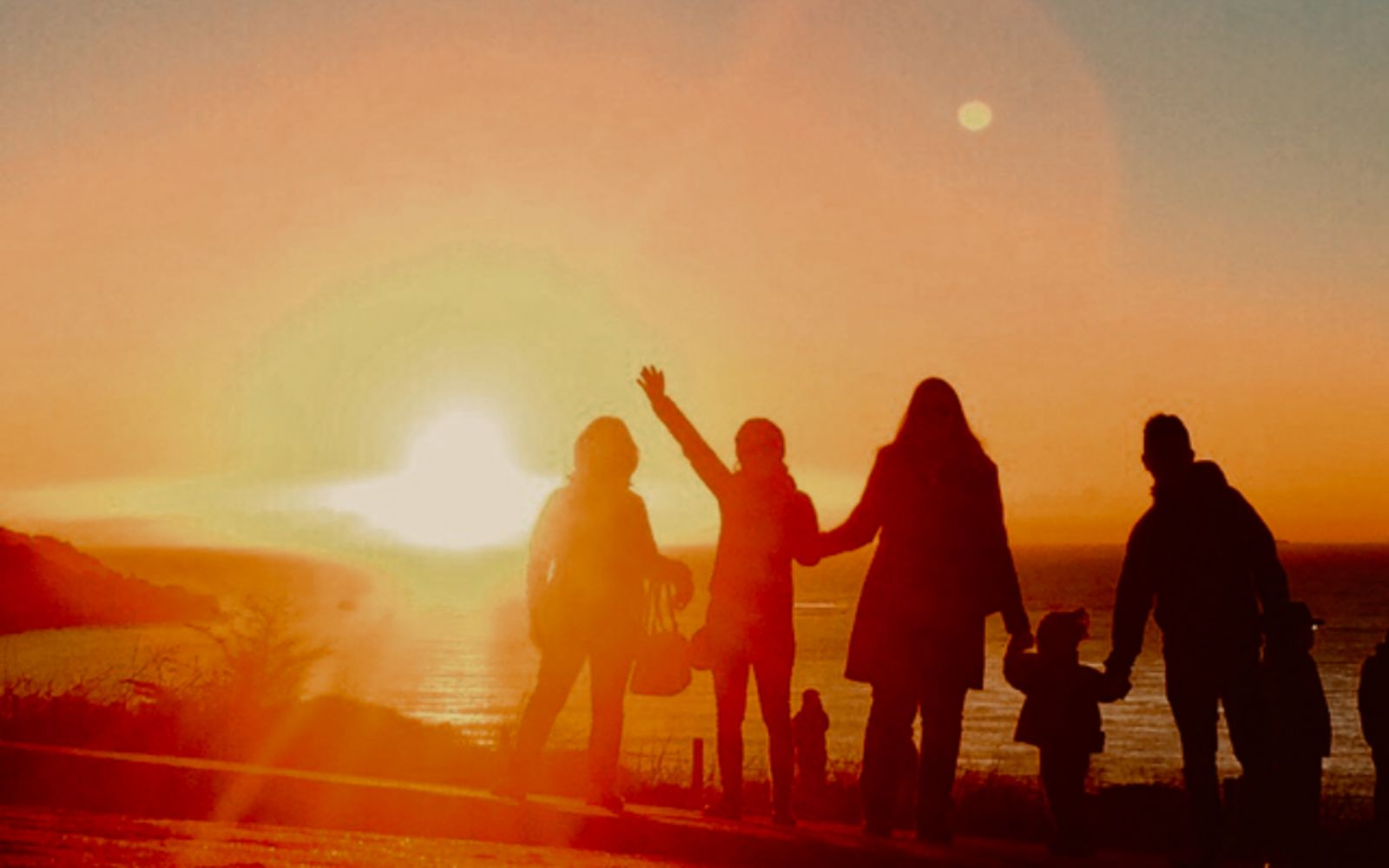 Family waving at sunset