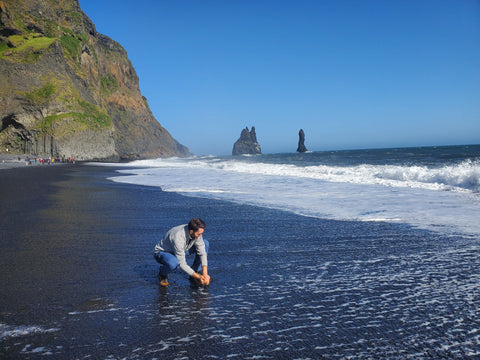 man gathering sand from Vik Beach Iceland so that his wedding rings can be made out of the sand