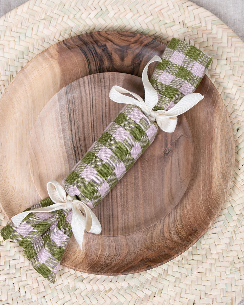 A handmade christmas cracker on wooden plates and palm leaf woven placemats by Bohemia Design