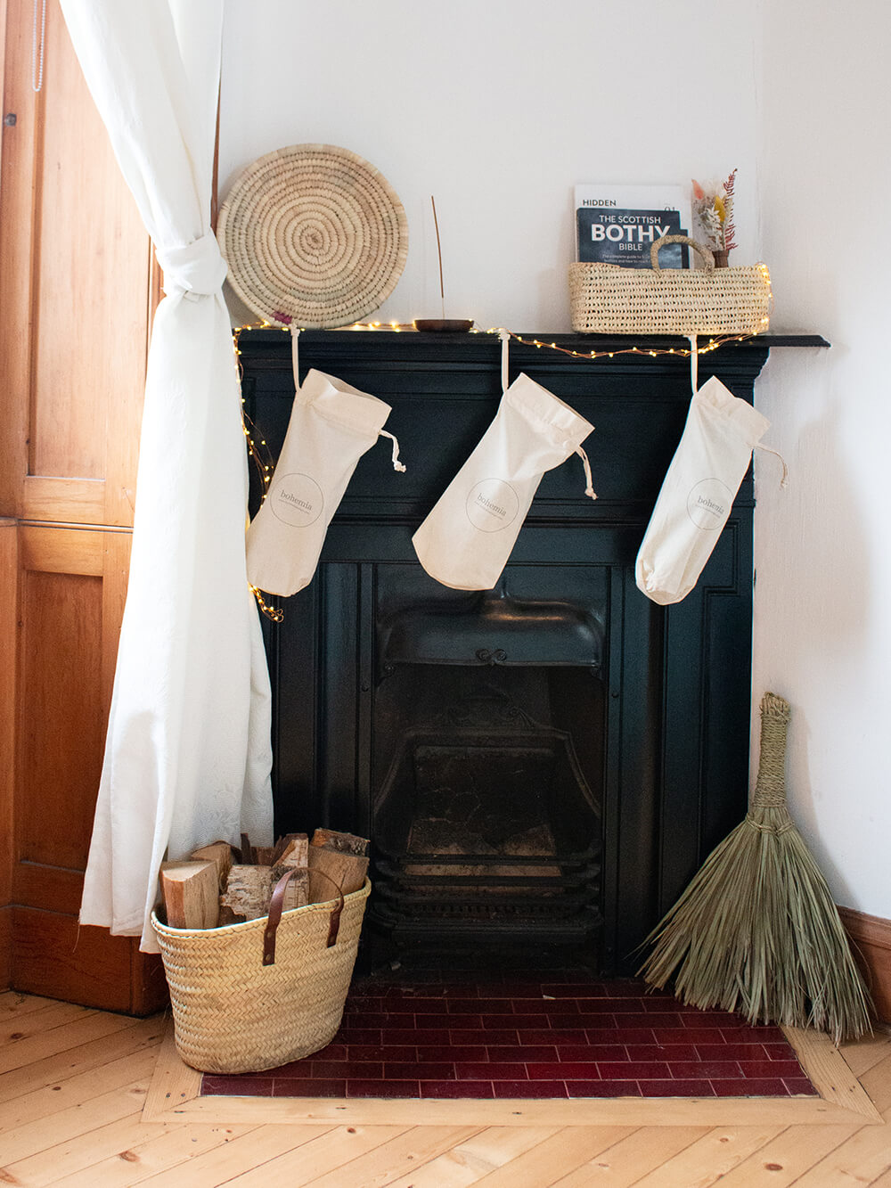 A black iron fireplace with white stockings and a basket with firewood