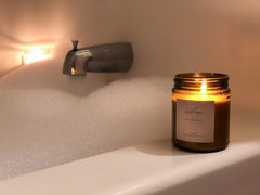 Lit candle next to bubble bath 