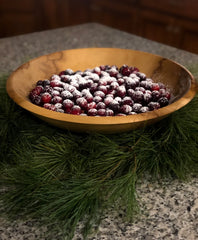 Christmas scene with wooden bowl filled with sugar dusted cranberries on evergreen bough