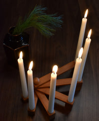 Wooden candle holder lit on table in dark room 