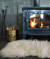 Sheepskin rug on floor beneath cozy wood fire 