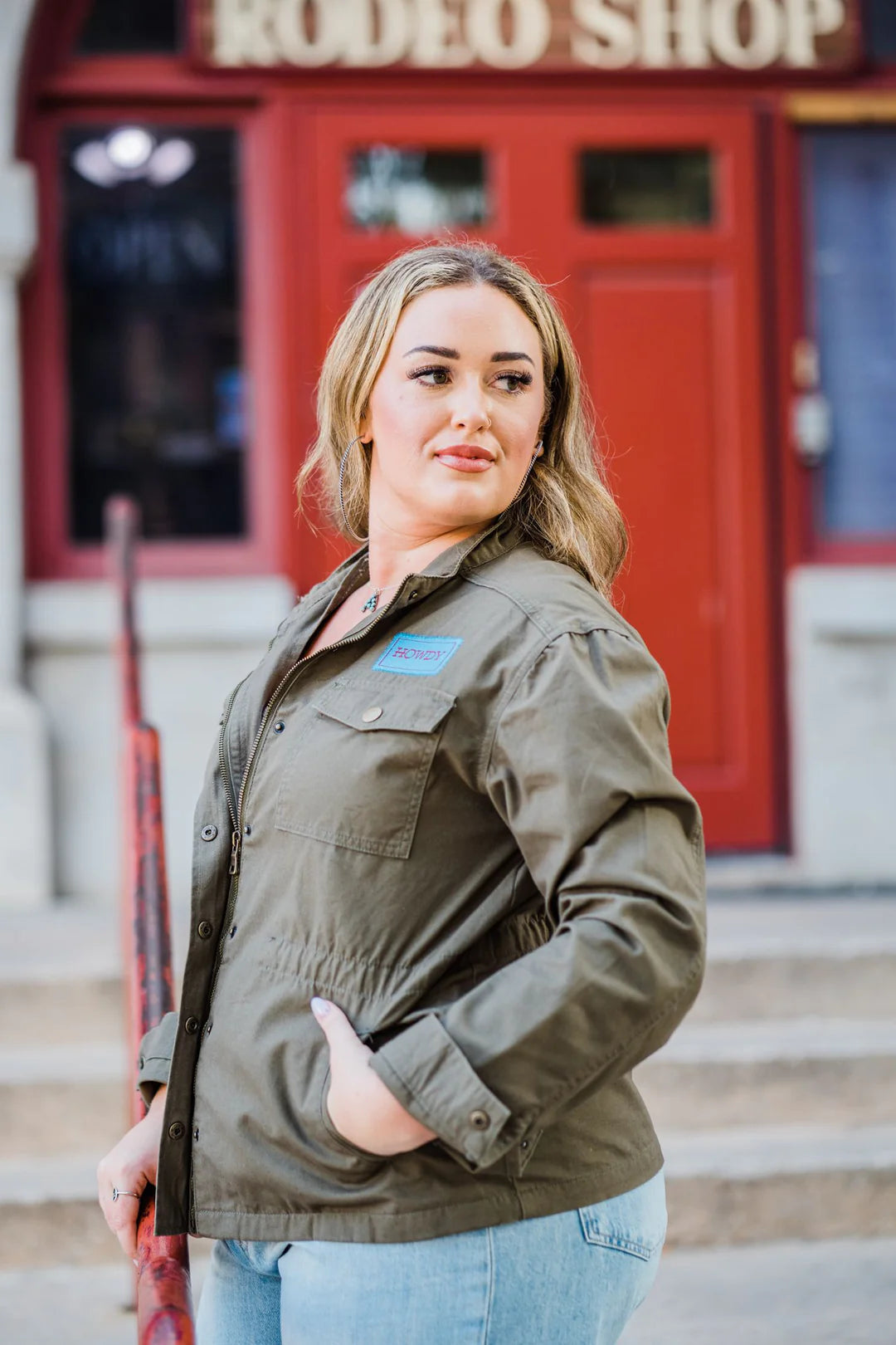 a woman in an army green jacket and jeans