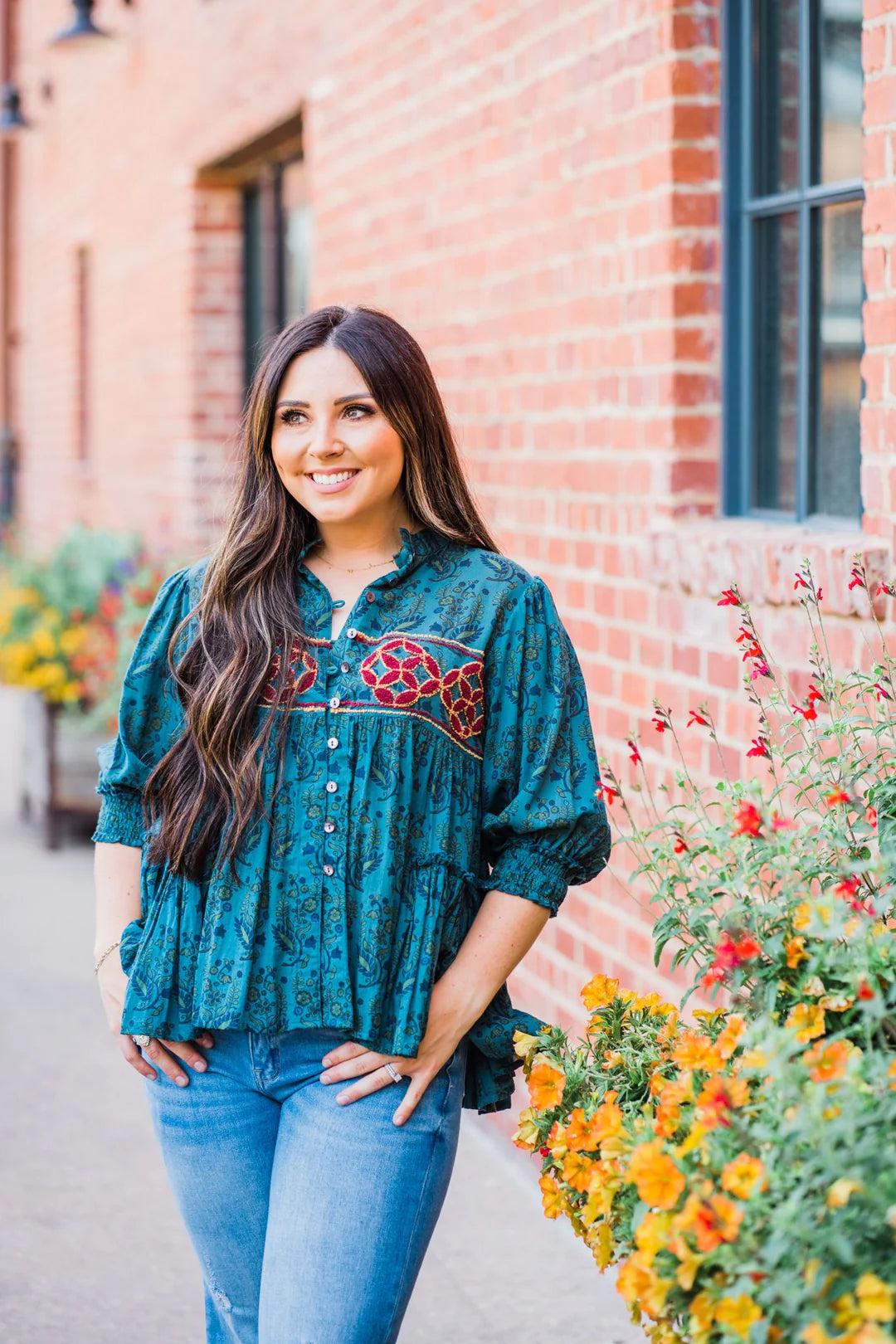 a woman in a blue patterned blouse and jeans