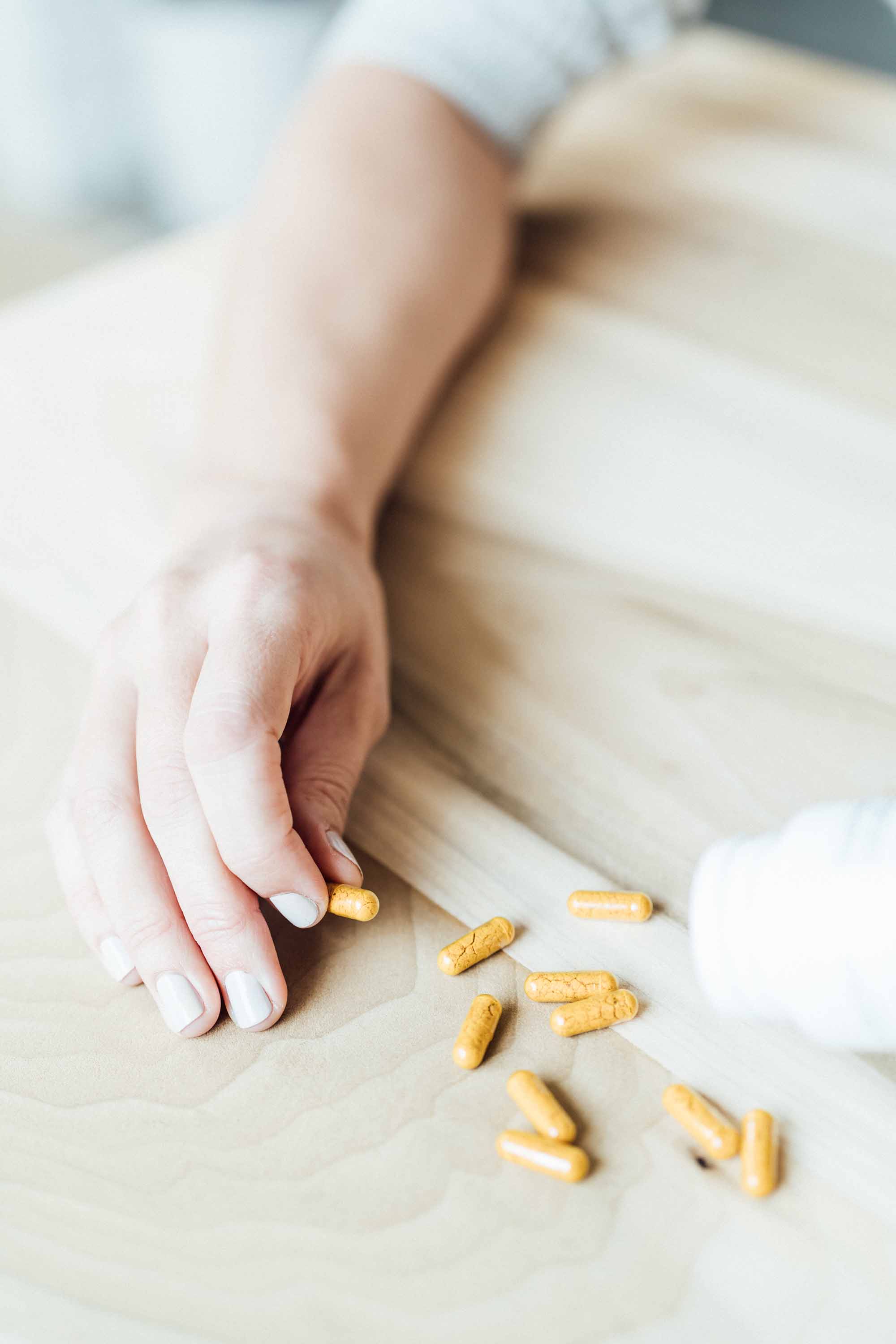 A female hand taking Sagely Naturals CBD Capsules out of the bottle