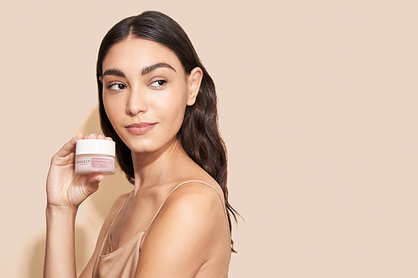 A woman holding a jar of Sagely Naturals Brightening CBD Night Cream