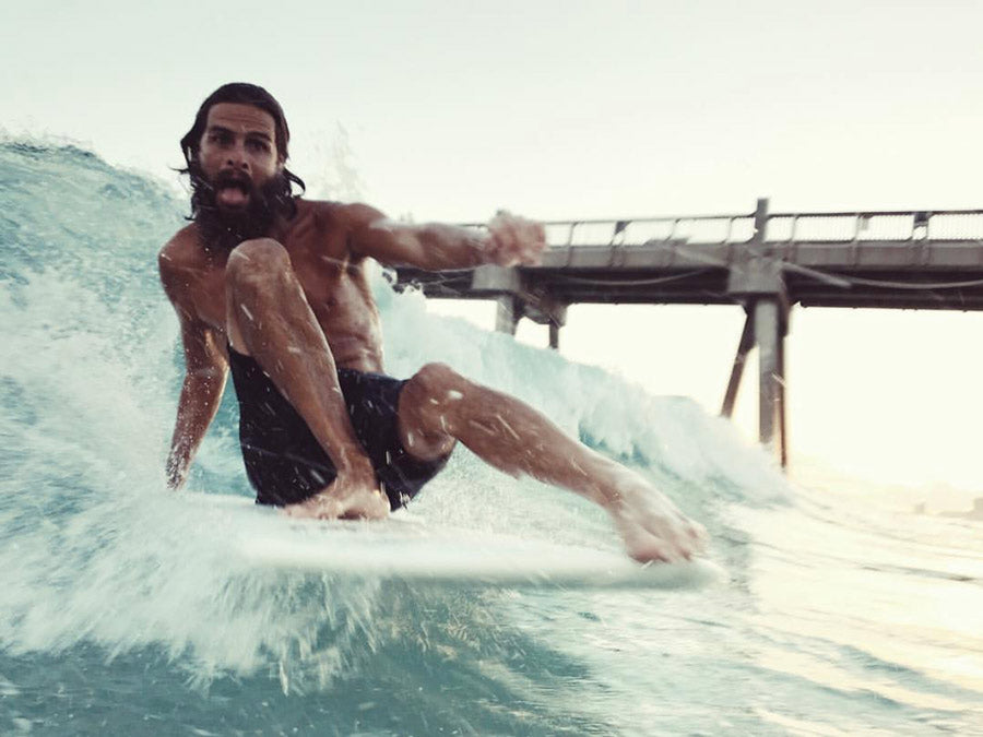 Sterling Spencer riding a wave on his surf board posing for the camera.