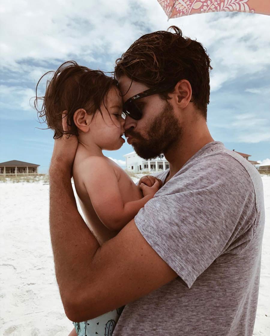 Sterling Spencer holding his son at the ocean.