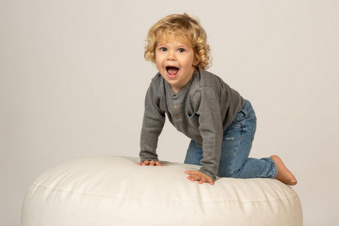 toddler posing on a posing beanbag for newborn photography