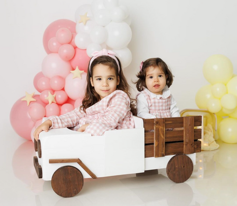 two sisters posing for photo inside a pickup truck prop