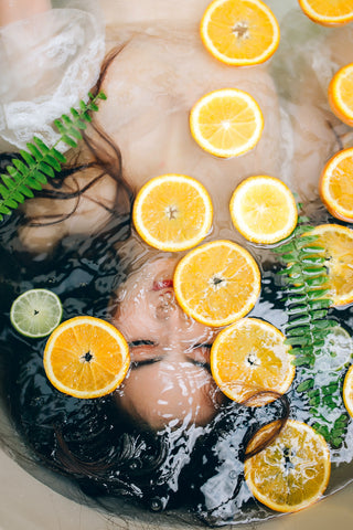 woman face up in water with orange, lemon slices all over