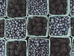 pints of blueberries and blackberries at a farmers market.  face down shot