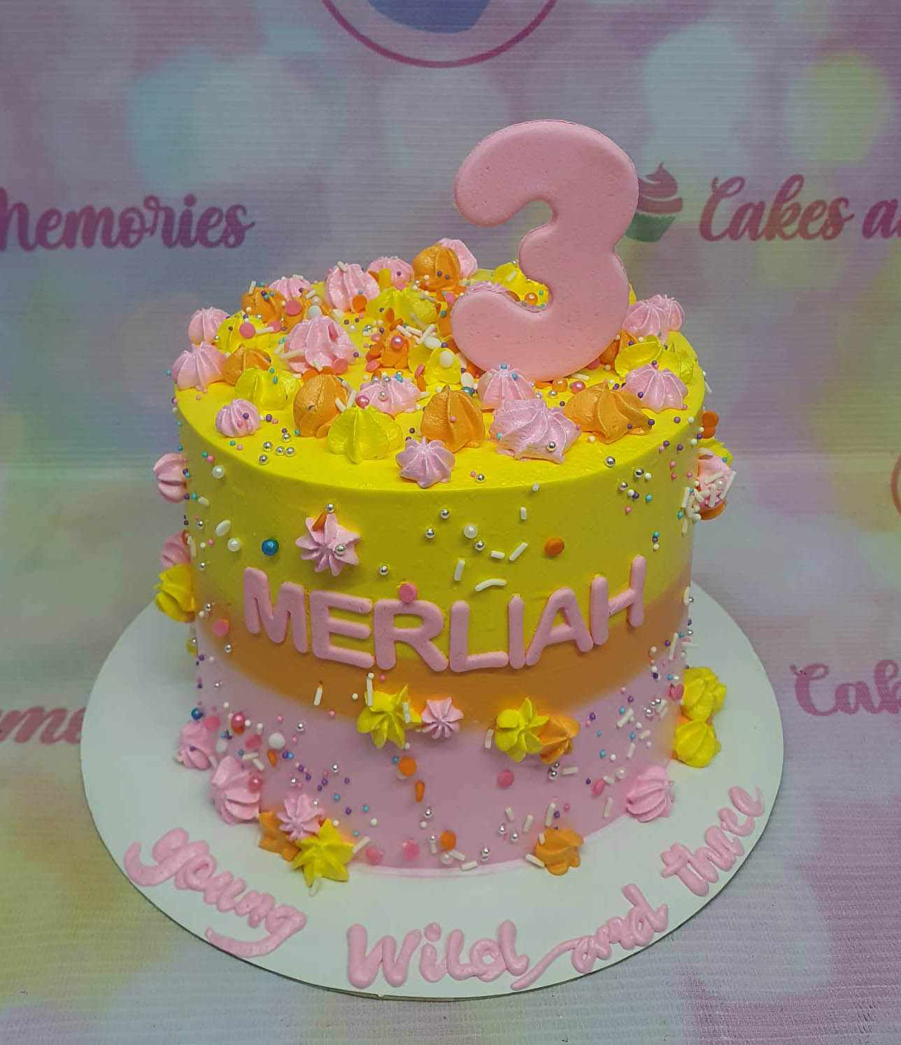 This custom decorated Candyland Cake is a 1 layer, 1 tier cake with colorful candy sprinkles, orange, pink, yellow, and Young Wild and Three.