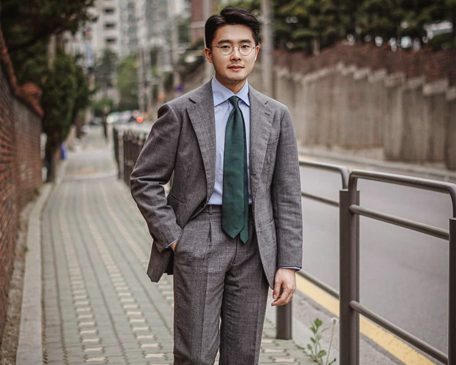 MQLee wearing a grey suit with green tie