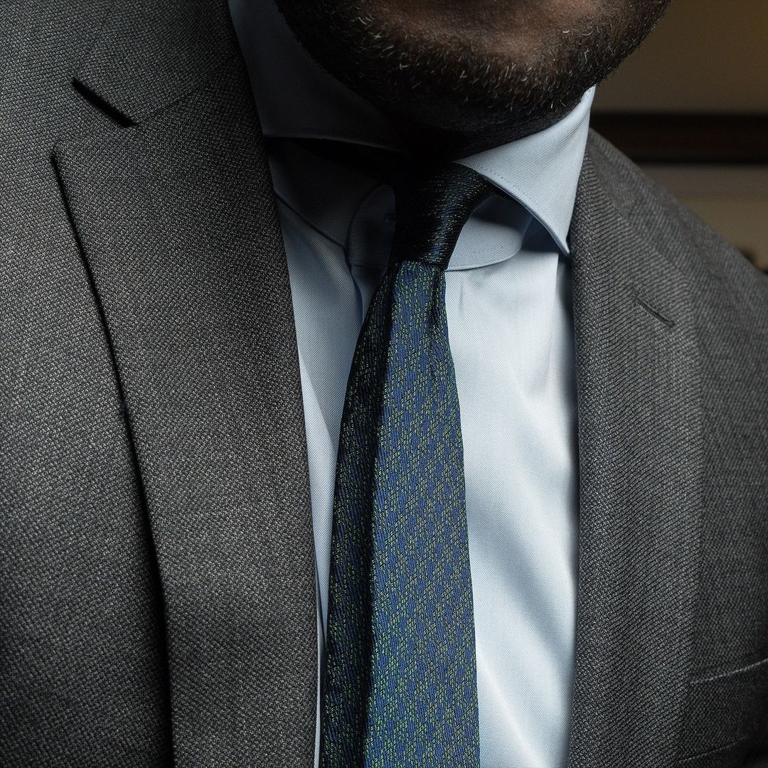 Aklasu Green and Navy Houndstooth Six-Fold Tie worn with a blue shirt and grey suit.