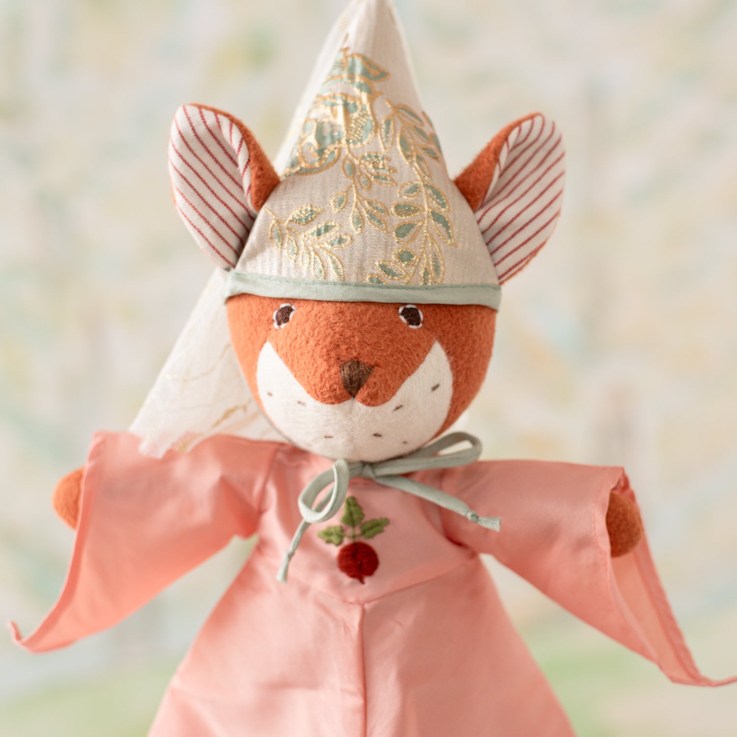 Portrait of Flora Fox wearing pink princess gown with pointy sleeves and an embroidered radish on the front, and a green and gold cone-shaped princess hat
