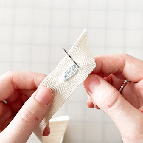 stitching the buttonhole in light blue thread